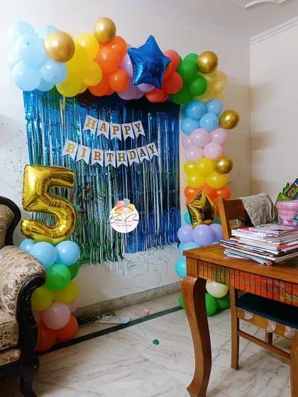 A colorful balloon arch with a blue shimmer curtain for a 5th birthday party at home.