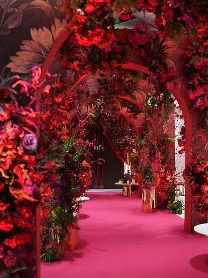 Who says an entrance can't be the main event? I designed this passionate, red-on-red floral tunnel to create a dramatic and immersive first impression. The layered arches and dense crimson blooms guide guests into a world of warmth and bold elegance, setting an unapologetically glamorous tone for the evening.