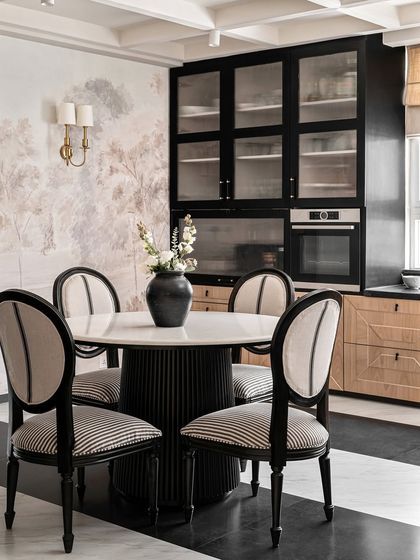 A closer look at the custom dining set and built-in cabinetry in the Riviera Maison project. The contrast of the black fluted table base and striped chairs against the natural oak and painted mural showcases our love for mixing textures and styles.