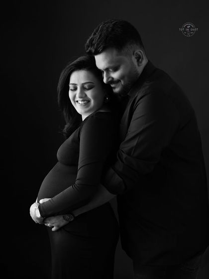 A timeless black and white portrait capturing a tender embrace between an expecting couple.