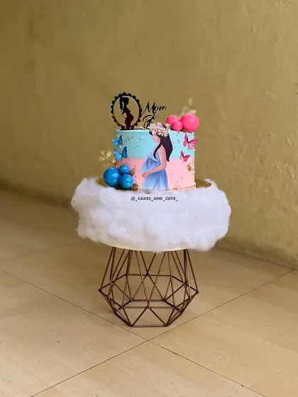 A whimsical "Mom to be" cake with a dreamy cloud-like base. The pink and blue colors with butterfly accents make it perfect for a baby shower.