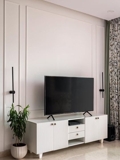 A favorite shot from "The White Oasis" project. This Scandinavian-style living room features a clean, white TV unit with fluted doors, simple wall molding, and minimalist black wall sconces for a look that is both elegant and serene.