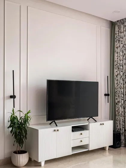 A favorite shot from "The White Oasis" project. This Scandinavian-style living room features a clean, white TV unit with fluted doors, simple wall molding, and minimalist black wall sconces for a look that is both elegant and serene.