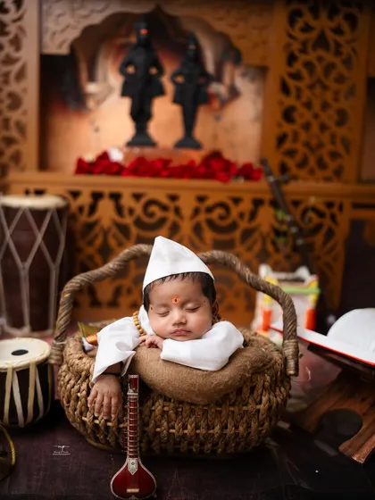 A tiny Varkari pilgrim dreams in his basket, surrounded by traditional instruments. I take great care in styling these cultural newborn sessions to be both authentic and adorable.