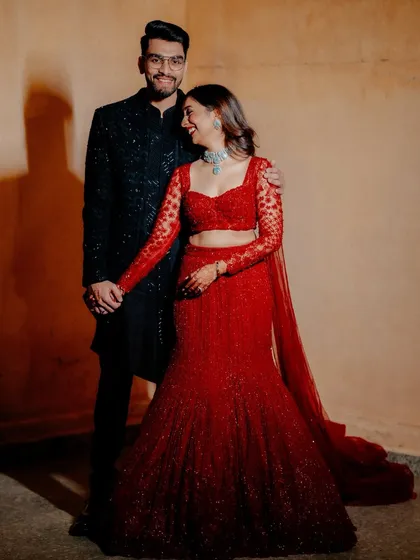 A candid, happy moment between this couple during their sangeet. Her stunning red lehenga and his classic black sherwani made for a picture-perfect combination.