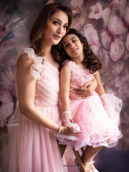 A beautiful mother-daughter portrait in matching pink dresses. This elegant studio session captures their graceful bond and creates a timeless piece of art.