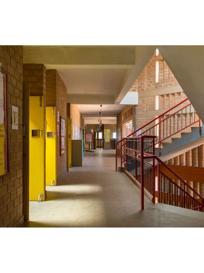 The main corridor at Buddhi School, with a view towards the staircase. The exposed earth block walls and openings into the courtyard create a bright and airy circulation space that connects different parts of the school.