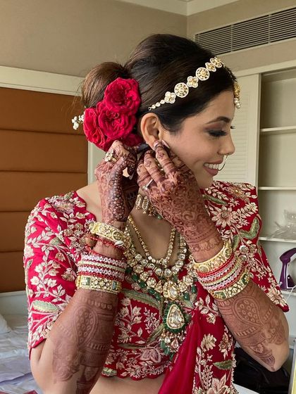 A happy bride getting ready, showing off her red rose bridal bun.