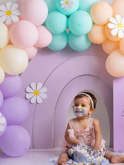 The full scene of the pastel cake smash. The combination of the props, balloons, and the messy baby creates a picture of pure birthday joy.