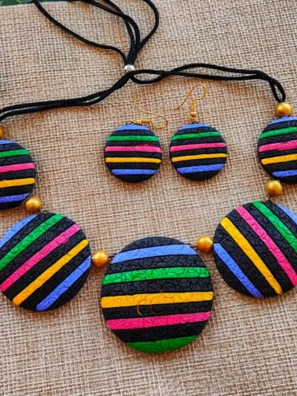I created this modern necklace using striped circular pendants with a unique texture. This version features bright, rainbow-like stripes on a black background, making it a fun and stylish piece.
