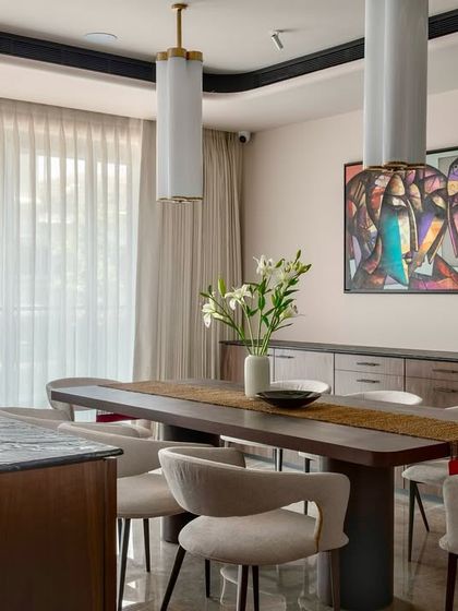 A different angle of the Parishram dining room, showcasing the modern, sculptural chairs and the dramatic artwork that anchors the space.