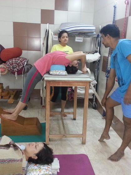 An older memory from a class, showing a student in a deep backbend over a bench. I am guiding her to ensure the pose is performed with precision and safety.