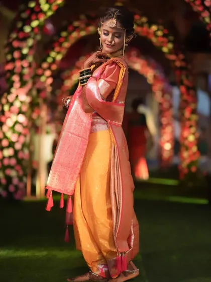 A stunning shot of the bride under an arch of flowers, her traditional attire looking magnificent.