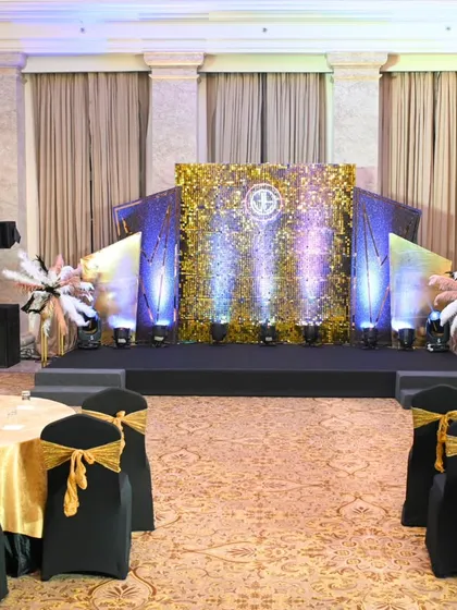 The main stage and seating arrangement for a Great Gatsby party. The gold sequin backdrop and dramatic lighting create a stunning focal point for the evening's festivities.