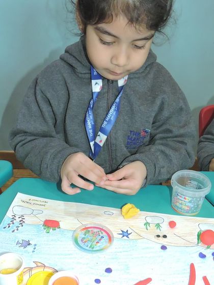 This student is deeply focused on her intricate clay project, carefully adding small details to her aquatic scene.