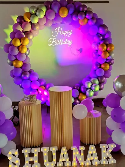 A purple and gold balloon ring with dramatic mood lighting for a stylish birthday party.