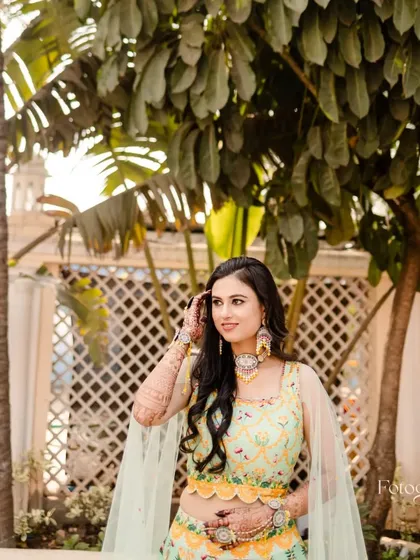 A beautiful bride, her mehndi-adorned hands framing her happy face. The intricate design is a perfect complement to her festive attire.