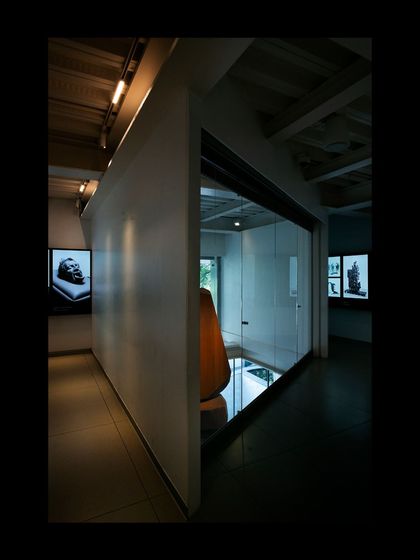 A gallery space within the Museum of Art and Photography (MAP), where a glass wall provides a visual connection to an adjacent area. The design balances the need for controlled gallery environments with a desire for spatial openness and flow.