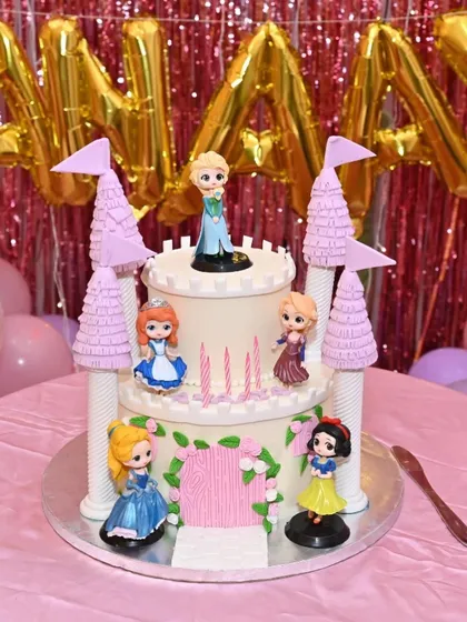 A fairytale Disney Princess castle cake. This two-tiered design features towers and beloved princesses like Elsa, Snow White, and Cinderella, creating a magical centerpiece.