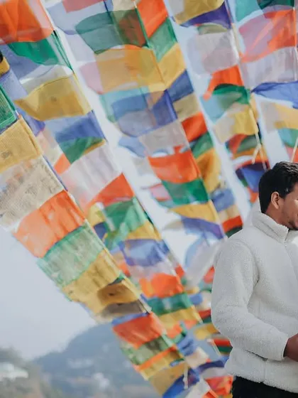 A beautiful portrait of the couple amidst colorful Tibetan prayer flags in Mussoorie. The vibrant flags create a stunning and meaningful backdrop for a romantic photo.