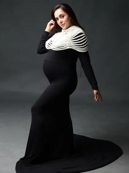 Bump love and glow goals. This classic black dress, accented with a statement pearl piece, creates a look of timeless sophistication.