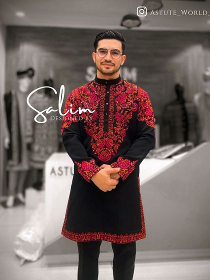 A client wearing a black kurta with vibrant red and pink floral embroidery around the neck and cuffs. The bold colors make this a standout piece.
