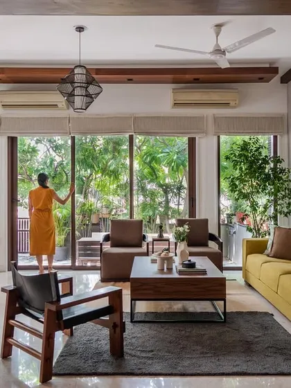 Creating a fluid connection between the indoors and outdoors is central to our design ethos. In this living room, floor-to-ceiling glass doors open up to a verdant garden, filling the home with natural light and creating a tranquil, airy atmosphere that embodies tropical modernism.