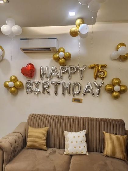 A simple and elegant wall decoration for a 75th birthday. Silver foil balloons are accented with gold and white balloon flowers, creating a tasteful and celebratory look.