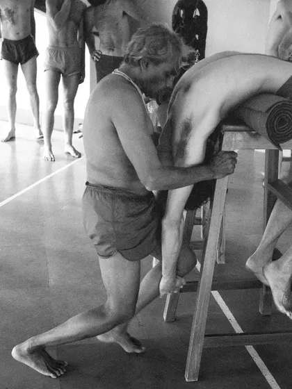 Guruji B.K.S. Iyengar providing a hands-on adjustment. His ability to see and correct the subtle misalignments in a student's body was legendary, born from decades of intense self-practice and observation.