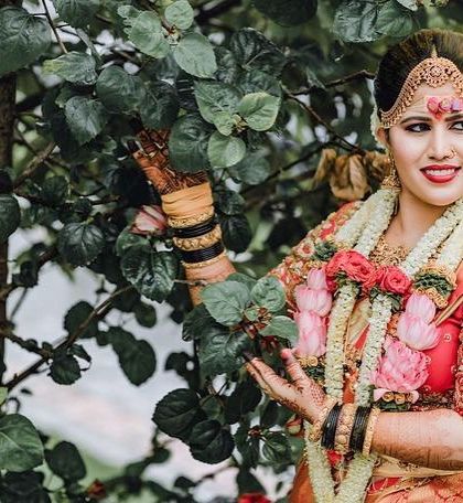 The complete traditional look, with fresh flower garlands complementing the bride's makeup and attire. The red bindi and bright smile complete this perfect Muhurtham portrait.