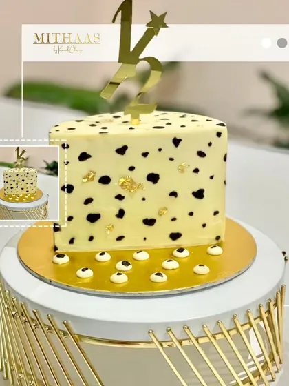 A playful yet elegant half-birthday cake. The square tier features a fun, dalmatian-like pattern made with natural black coloring, accented with gold leaf and a custom gold "1/2" topper.