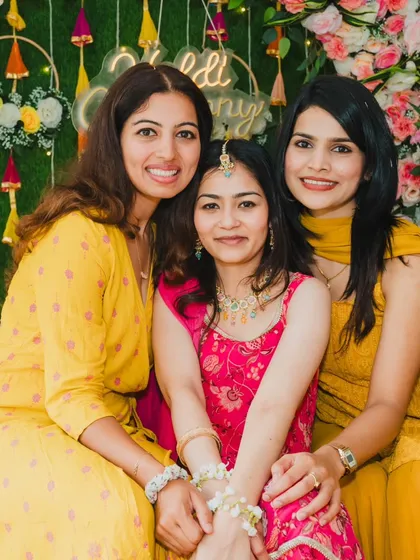 The bride posing with her friends during her Haldi ceremony, all dressed in beautiful shades of yellow and pink.