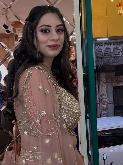 A candid shot of the client in her peach and gold lehenga, showing how the makeup looks natural and beautiful even in a relaxed pose.