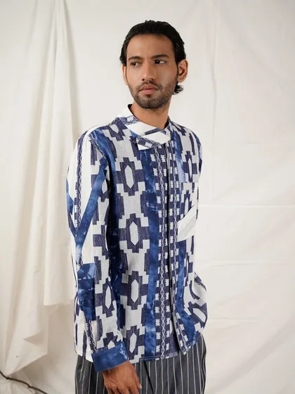 A male model in a striking blue and white geometric print shirt. The clean studio background ensures the bold pattern is the main focus of the image.