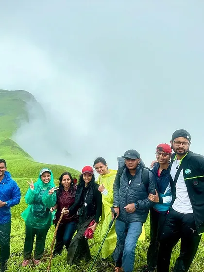 A happy group of trekkers on a misty mountain trail, enjoying the cool weather and beautiful scenery.