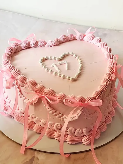 "Hello 17." A pretty pink heart-shaped vintage cake decorated with delicate piping and pink ribbons. A sweet and stylish way to celebrate a 17th birthday.