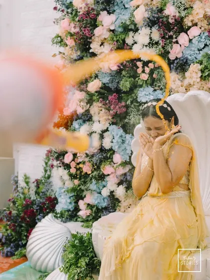 A dynamic action shot of the bride being playfully splashed with turmeric water during her Haldi ceremony. Her expression of surprise and joy is priceless.