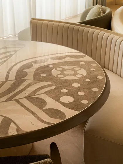 We see dining tables as centerpieces for stories and meals. This piece features a custom marble inlay top with sinuous patterns inspired by illustrator Jane Foster, crafted from Crema Marfil and Federal Beige marble. It’s paired with a fluted banquette, creating an intimate and artistic dining nook.