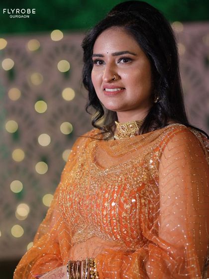 A happy client glowing in a beautiful sequined orange lehenga. This outfit is perfect for adding a touch of sparkle to any wedding celebration.