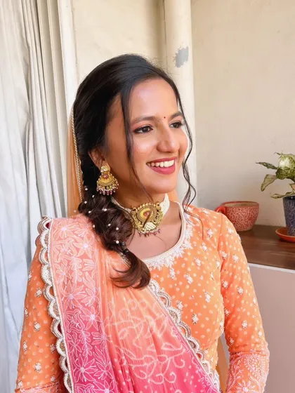 Radiance redefined. This look features a sun-kissed glow with a peachy-orange outfit, perfect for a daytime function. The makeup is minimal, with a focus on flawless skin.