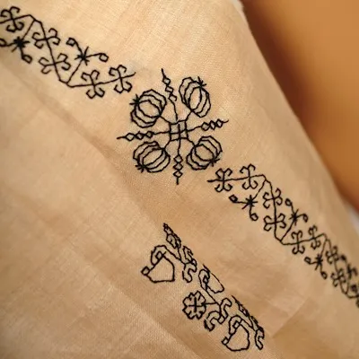 A simple yet elegant blackwork-style embroidery on a light-colored fabric. This type of counted-thread work is precise and graphic.