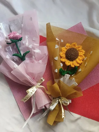 A lovely pairing of two single stem bouquets. On the left is a delicate pink flower, and on the right is our classic sunflower, both beautifully wrapped and ready to gift.