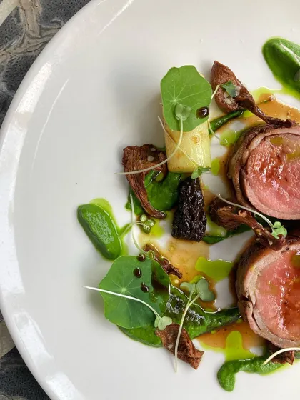 A close-up of the plated veal dish, showing the beautiful pink center of the meat and the earthy tones of the wild mushrooms.