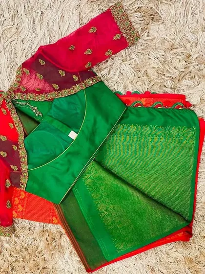 A classic combination of a green silk blouse with pink net sleeves, paired with a green and pink silk saree.