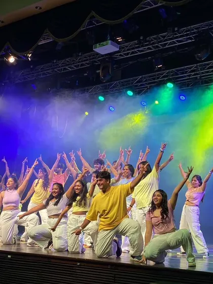 A high-energy moment from a modern dance piece at 'Manch 24.' The pastel color palette and dynamic group pose create a fresh and youthful vibe.