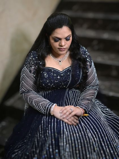 Unapologetically glamorous. This bride's reception makeup is dark and sultry, with a smokey eye that adds drama to her sparkling navy blue lehenga.