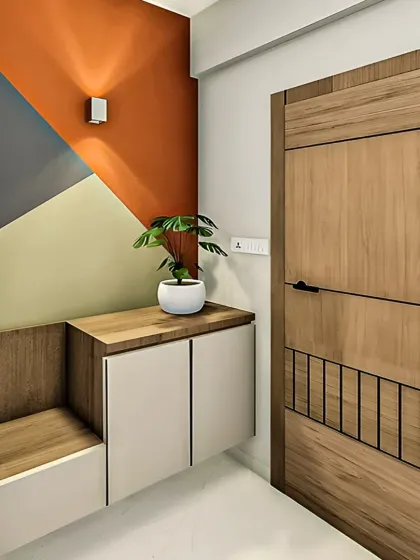 A well-designed entryway sets the tone for your entire home. Here, we combined a floating shoe cabinet with an integrated seating bench, using a mix of wood and white finishes and a bold, geometric accent wall to create a welcoming and organized first impression.