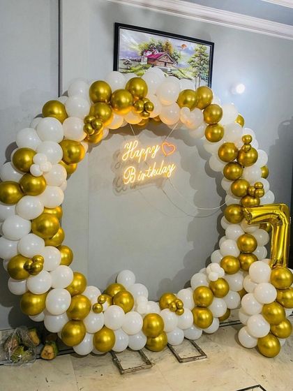 A white and gold balloon ring with a foil number '7', showing a simple yet beautiful setup for a child's birthday at home.