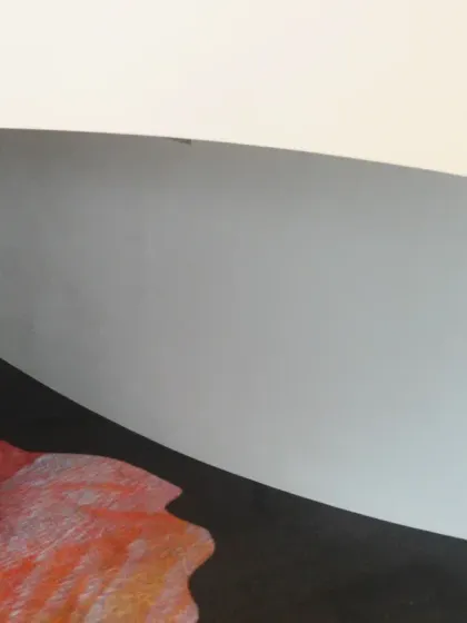 A detail of the curved wall and the 'Amorphous Color Rain' projection at the Novartis Campus. The image highlights the contrast between the minimal white architectural surface and the fluid, colorful artwork.