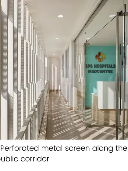 The public corridor at SPS Hospital Clinic features a perforated metal screen. This facade element filters natural light, creating dynamic patterns of light and shadow while maintaining a connection to the outside.